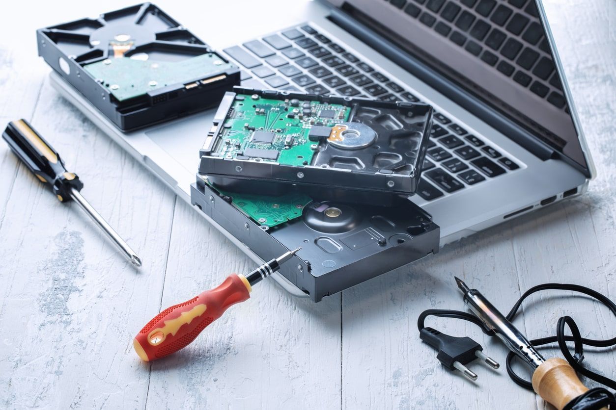 Opengemaakte harde schijven en gereedschap naast een laptop